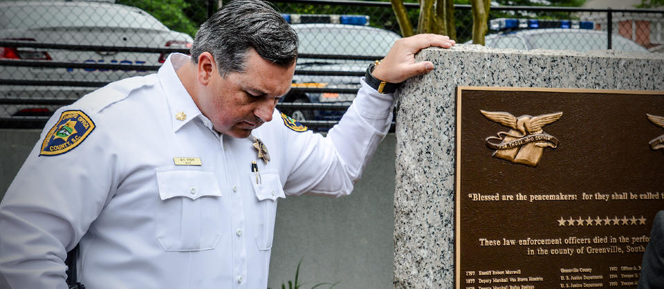 Fallen Heroes - officer leaning on memorial